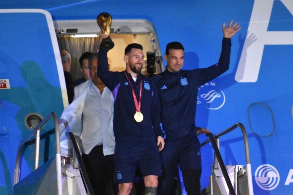 Lionel Messi muestra la Copa del Mundo, al arribar al Aeropuerto de Ezeiza. A su lado, Scaloni y Tapia.