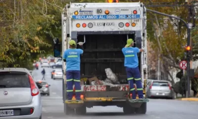 Dos obreros sobre el estribo de un camión de recolección de residuos de la empresa Cliba.